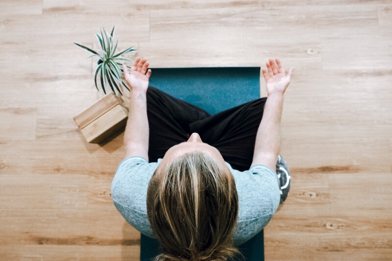 femme en tailleur médite sur un tapis